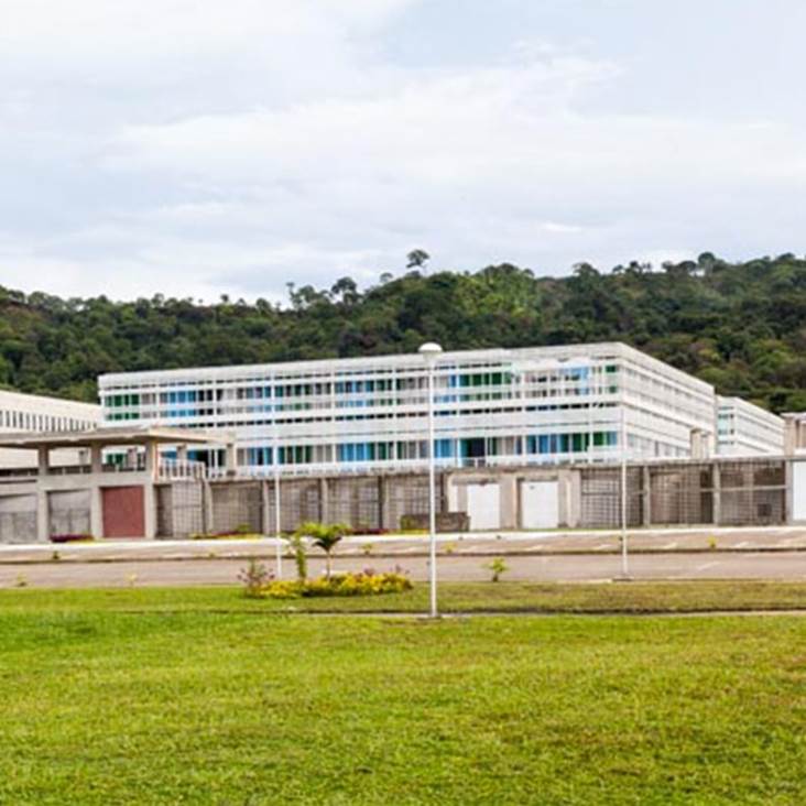 A large white building with a grassy field

Description automatically generated